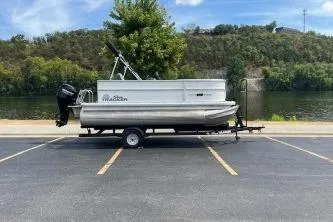 Slide: The Image of 2026 Sun Tracker Bass Buggy 16 DLX pontoon boat on trailer, parked near a scenic river. - 6