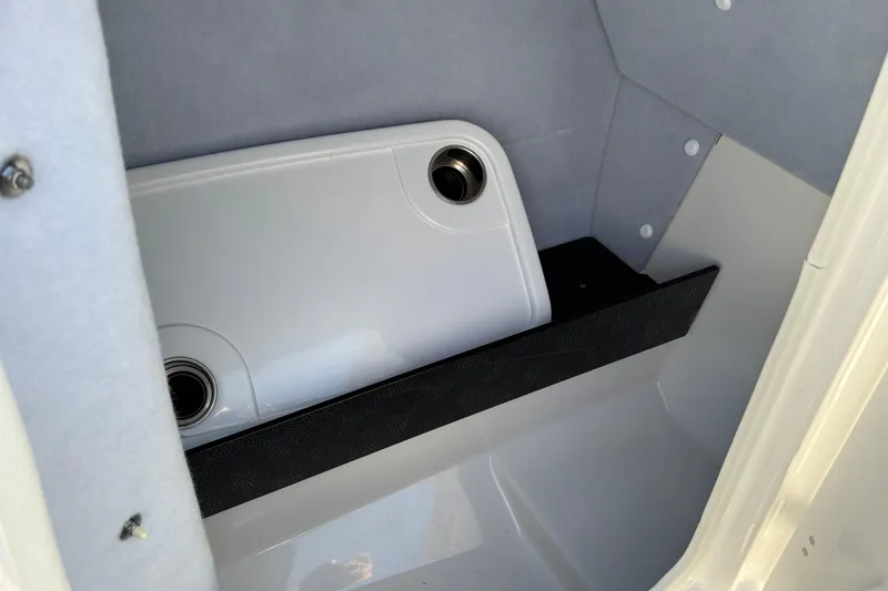 Slide: The Image of Storage compartment in a 2020 Yamaha AR240 boat, featuring a white panel and cup holders. - 21