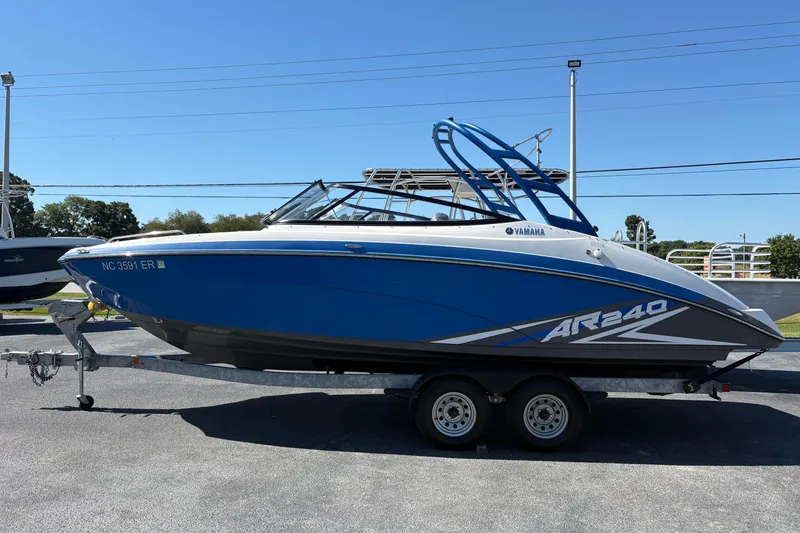 Slide: The Image of 2020 Yamaha AR240 boat on trailer, blue and white design, parked outdoors. - 3