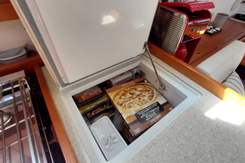 Slide: The Image of Freezer compartment on 2015 Beneteau Oceanis 45 yacht with frozen meals and pizza. - 56