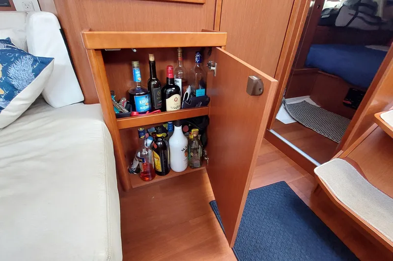 Slide: The Image of Bar cabinet inside a 2015 Beneteau Oceanis 45 yacht, stocked with various liquor bottles. - 61