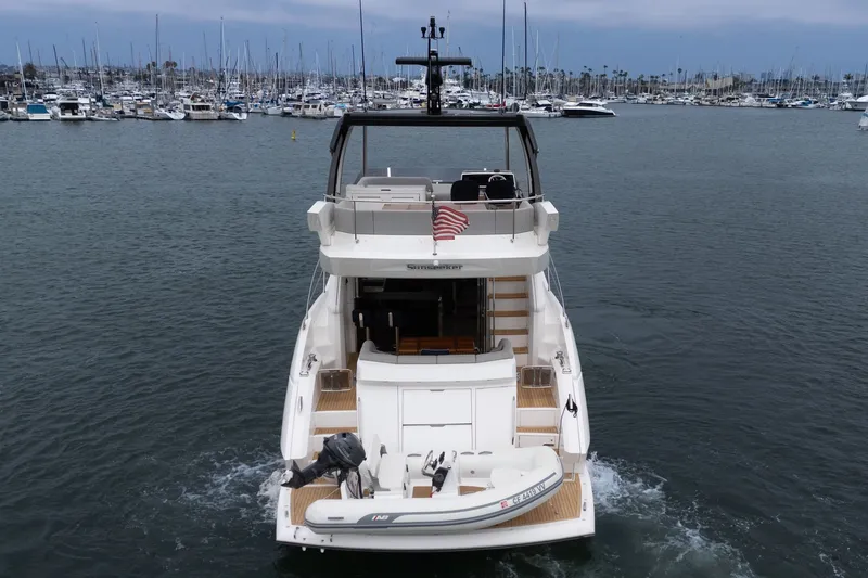 Slide: The Image of 2021 Sunseeker Manhattan 55 yacht cruising in a marina with numerous docked boats. - 28