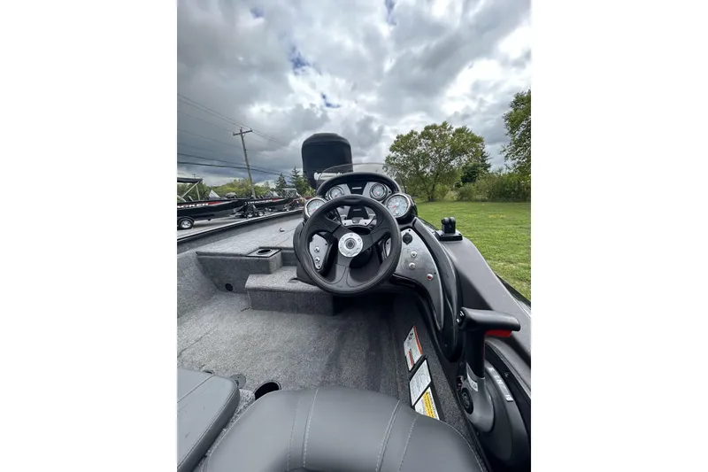 Slide: The Image of 2023 Tracker Pro Team 175 TXW boat interior with steering wheel and dashboard under cloudy sky. - 3
