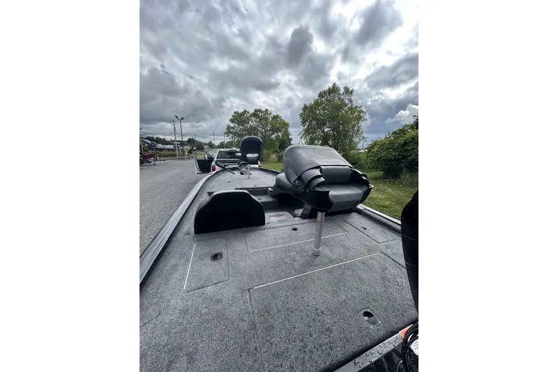 Slide: The Image of 2023 Tracker Pro Team 175 TXW boat interior with seating and storage, under cloudy sky. - 5