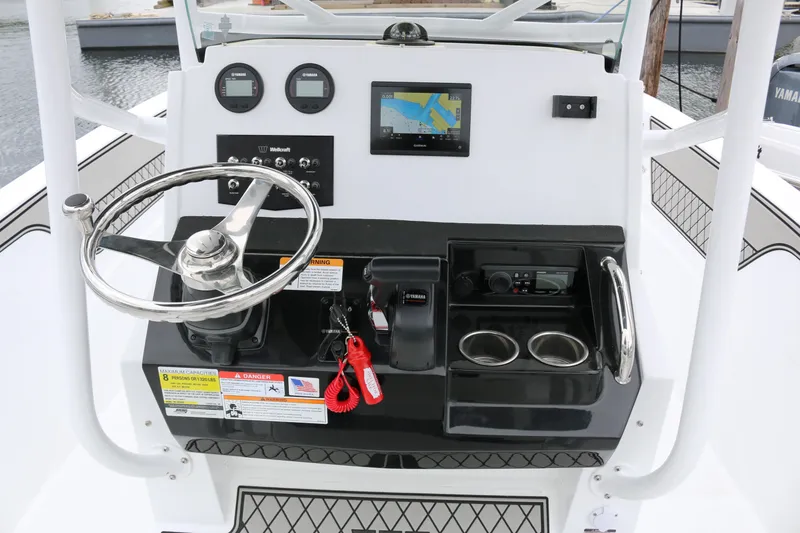 Slide: The Image of 2025 Wellcraft 202 Fisherman boat dashboard with steering wheel and navigation controls. - 17