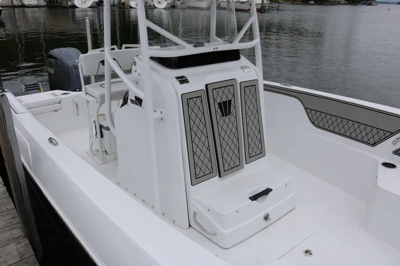 Slide: The Image of 2025 Wellcraft 202 Fisherman boat interior with seating and storage, docked by the water. - 8