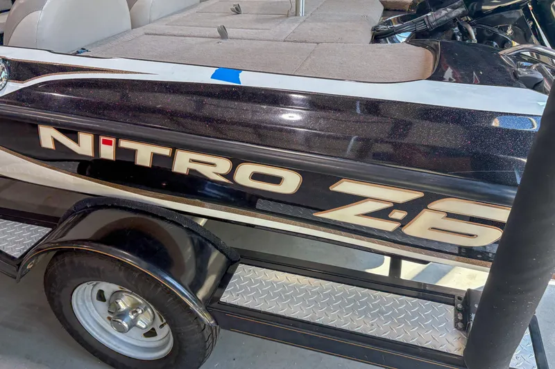 Slide: The Image of 2013 Nitro Z6 boat with sleek black design and logo, parked on a trailer. - 3