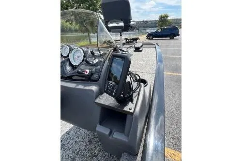 Slide: The Image of 2024 Tracker Pro 170 boat dashboard with steering wheel and gauges by a riverside. - 3