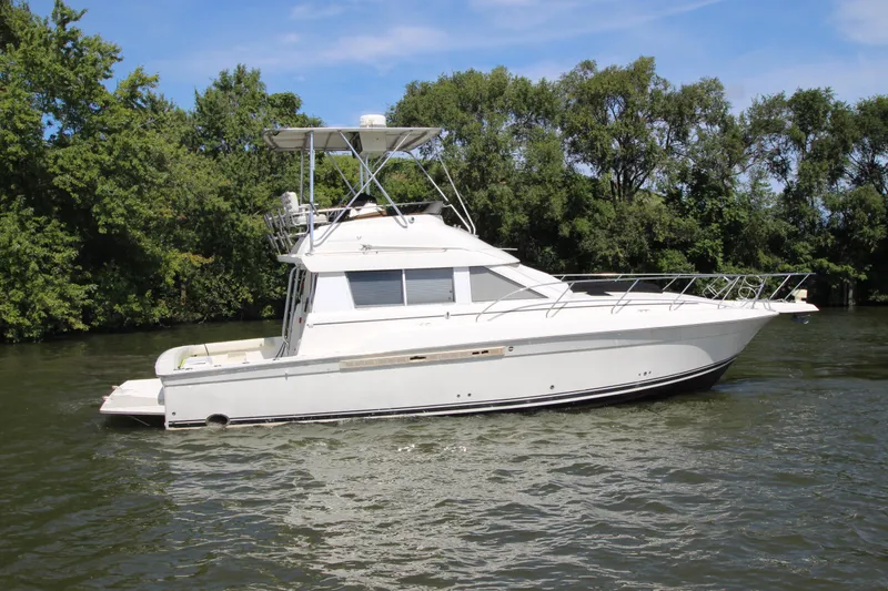 The Image of 2000 Silverton 37 Convertible yacht cruising on a scenic river. - 0