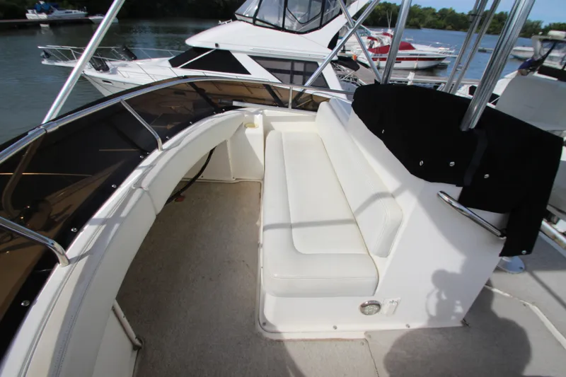 Slide: The Image of 2000 Silverton 37 Convertible yacht with white seating on deck, docked by the water. - 13