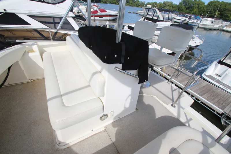 Slide: The Image of 2000 Silverton 37 Convertible boat interior with white seating and marina view. - 14