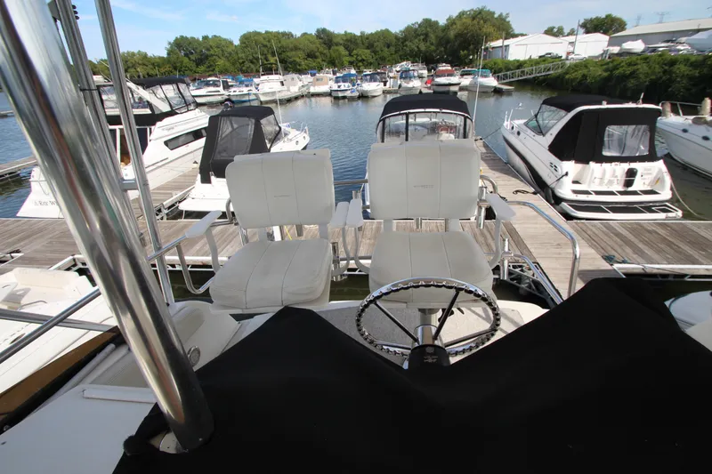 Slide: The Image of 2000 Silverton 37 Convertible yacht at marina, featuring helm and seating area. - 15