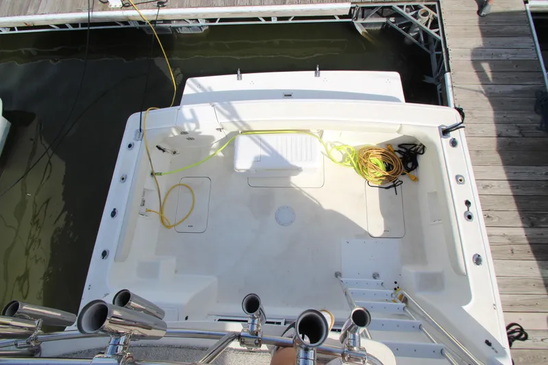 Slide: The Image of 2000 Silverton 37 Convertible boat deck with docked view, featuring coiled ropes and fishing rod holders. - 18