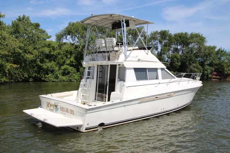 Slide: The Image of 2000 Silverton 37 Convertible yacht on a serene river, surrounded by lush greenery. - 3