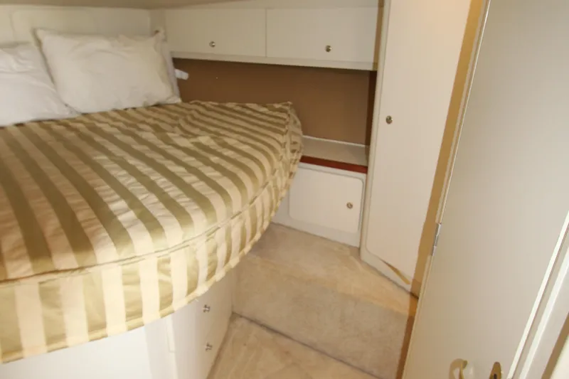 Slide: The Image of 2000 Silverton 37 Convertible cabin interior with striped bedding and storage cabinets. - 32
