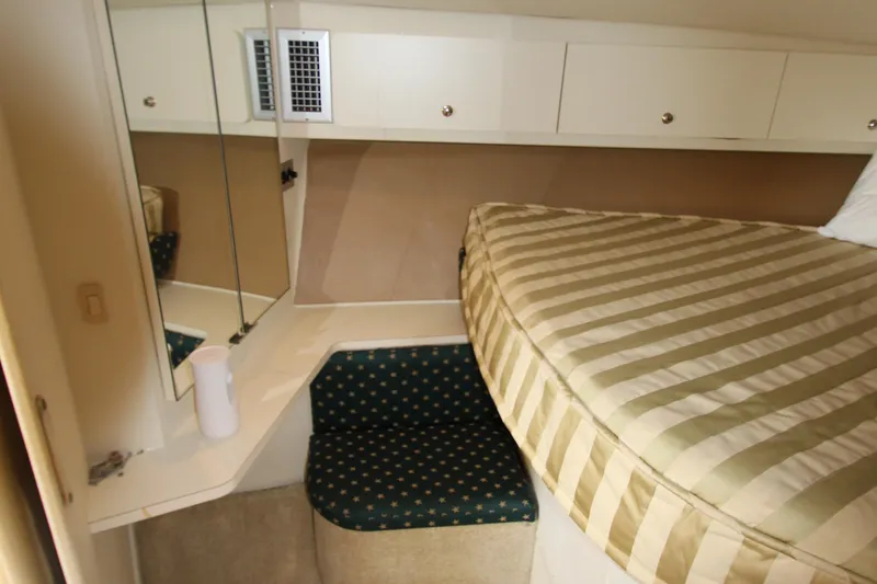 Slide: The Image of 2000 Silverton 37 Convertible cabin with striped bedding and mirrored storage. - 33