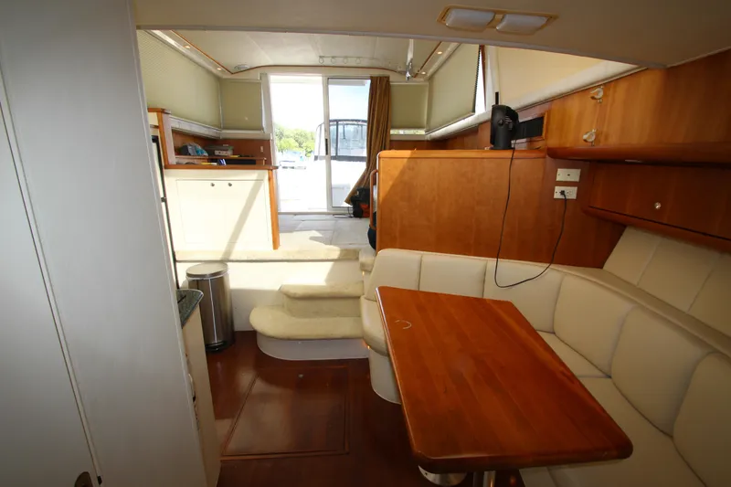 Slide: The Image of Interior of 2000 Silverton 37 Convertible yacht with wooden table and beige seating. - 34