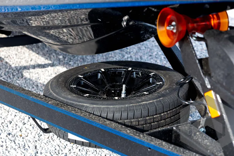 Slide: The Image of 2026 Skeeter FXR21 FLEX trailer with spare tire on gravel surface. - 12