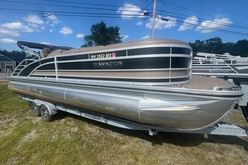 The Image of 2020 Bennington 25 RSB pontoon boat on trailer, parked on grass under blue sky. - 1