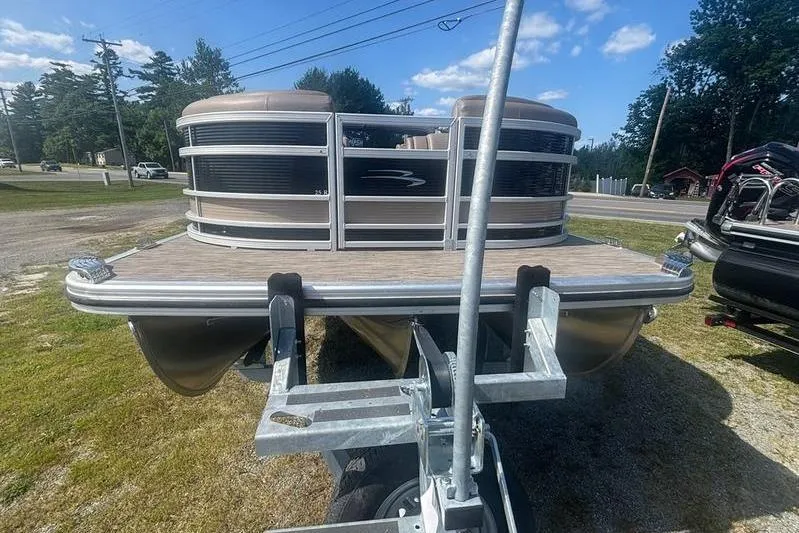 Slide: The Image of 2020 Bennington 25 RSB pontoon boat on trailer, parked outdoors under blue sky. - 6