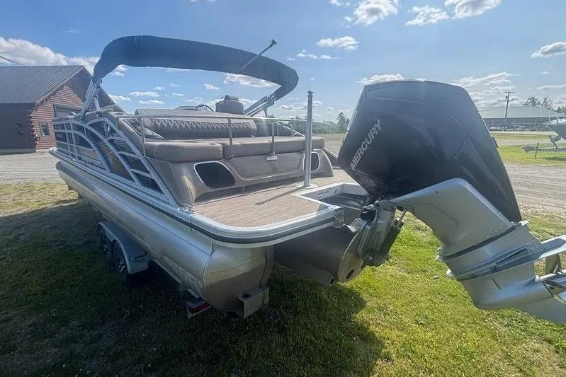 Slide: The Image of 2020 Bennington 25 RSB pontoon boat with Mercury outboard engine on grassy area. - 8