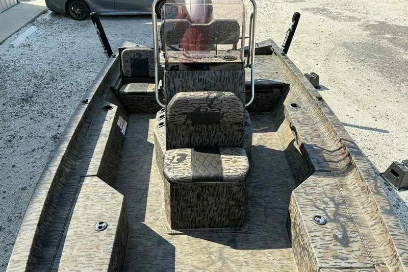 Slide: The Image of 2020 Xpress H20B Bay boat with camouflage interior, parked on gravel. - 13