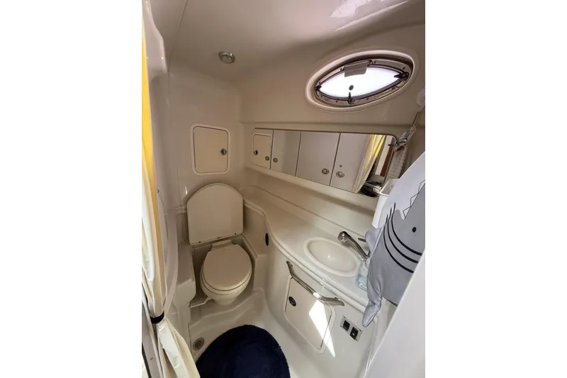 Slide: The Image of 2007 Sea Ray 320 Sundancer bathroom with toilet, sink, and porthole window. - 19