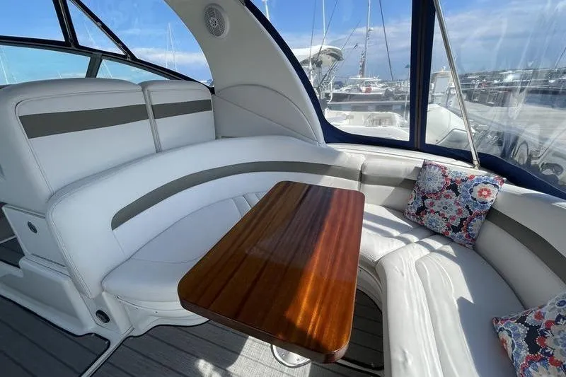 Slide: The Image of Interior of 2003 Sea Ray 320 Sundancer with white seating and wooden table. - 8