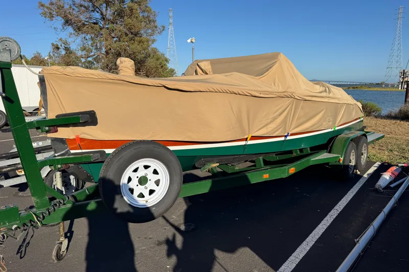 Slide: The Image of 1987 Grand Craft Triple Cockpit Runabout covered on trailer by a riverside. - 19