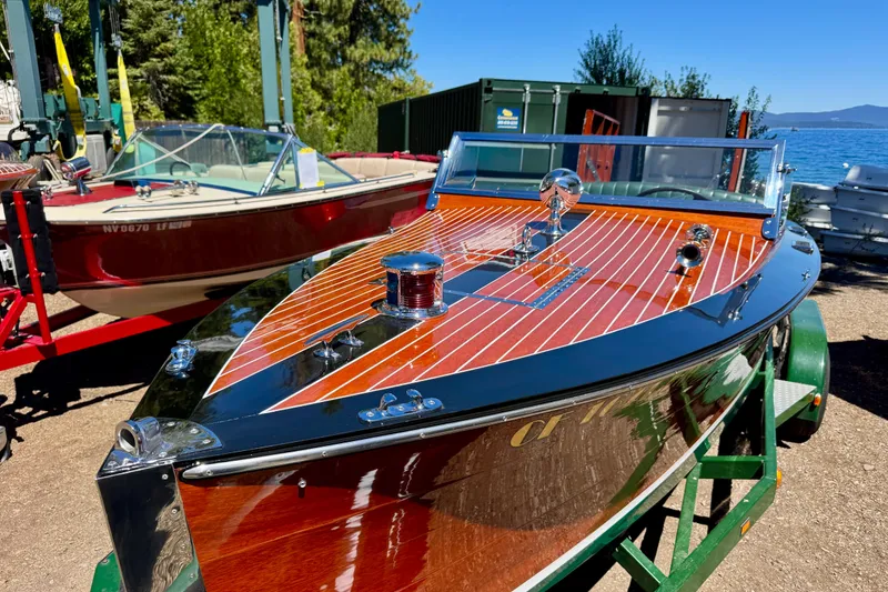 Slide: The Image of 1987 Grand Craft Triple Cockpit Runabout, polished wood finish, docked near a lake. - 8