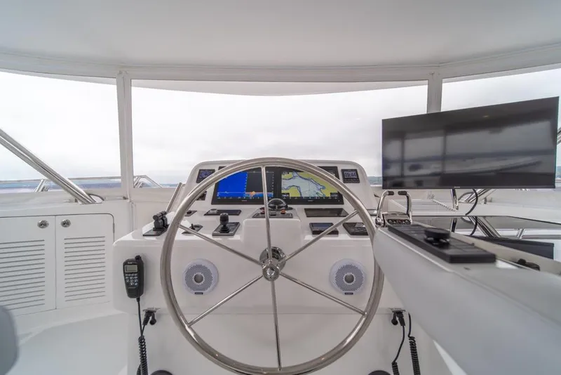 Slide: The Image of 2022 Outer Reef 720 Motor Yacht helm with navigation screens and steering wheel. - 86