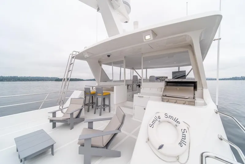 Slide: The Image of Luxurious 2022 Outer Reef 720 Motor Yacht deck with seating and grill, on calm waters. - 95