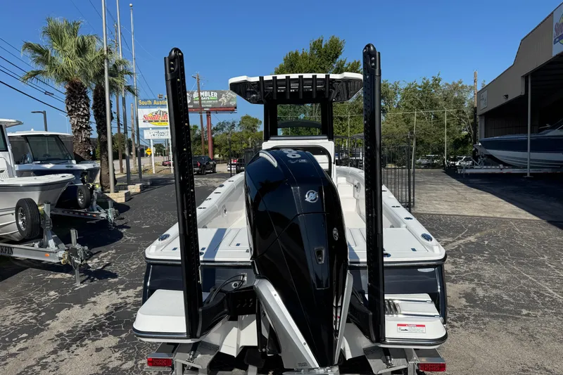 Slide: The Image of 2026 Blackfin 242HB boat with powerful outboard motor, parked outdoors on a sunny day. - 2