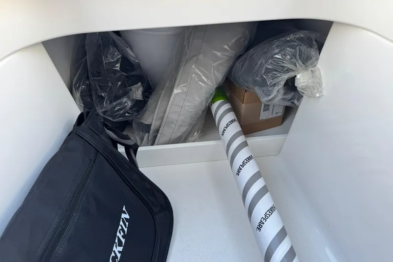 Slide: The Image of Storage compartment in a 2026 Blackfin 242HB boat with various items and a Blackfin bag. - 25