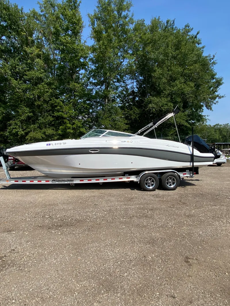 Slide: The Image of 2023 Hurricane SD 2690 OB boat on trailer, parked outdoors with trees in background. - 2