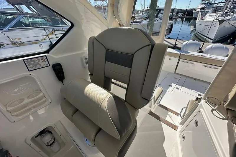 Slide: The Image of Captain's chair on 2020 Pursuit OS 355 Offshore boat, featuring beige upholstery and armrests. - 14
