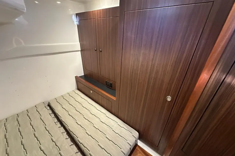 Slide: The Image of 2020 Pursuit OS 355 Offshore cabin interior with twin beds and wooden cabinetry. - 26