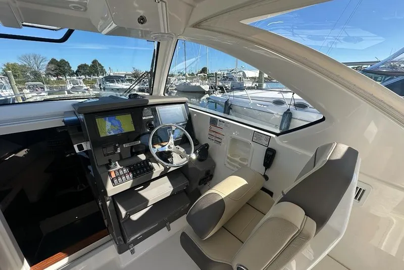 Slide: The Image of 2020 Pursuit OS 355 Offshore boat interior with covered seat, docked at marina. - 7