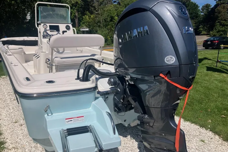 Slide: The Image of 2026 Sundance DX22 boat with Yamaha outboard motor, parked on gravel near grass. - 2