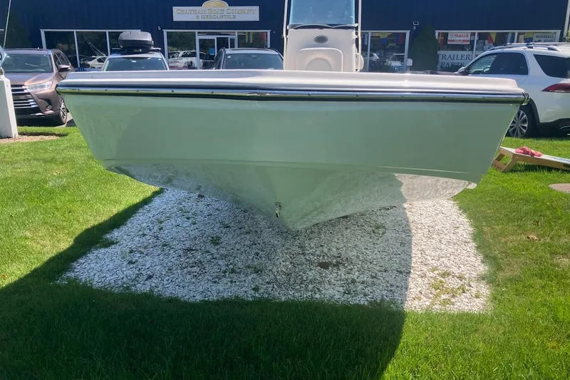 Slide: The Image of 2026 Sundance DX22 boat displayed on grass with gravel, surrounded by cars. - 3