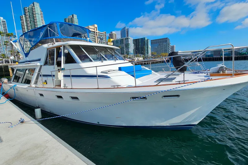 The Image of 1985 Bayliner 4550 Motoryacht docked in a marina with city skyline backdrop. - 0