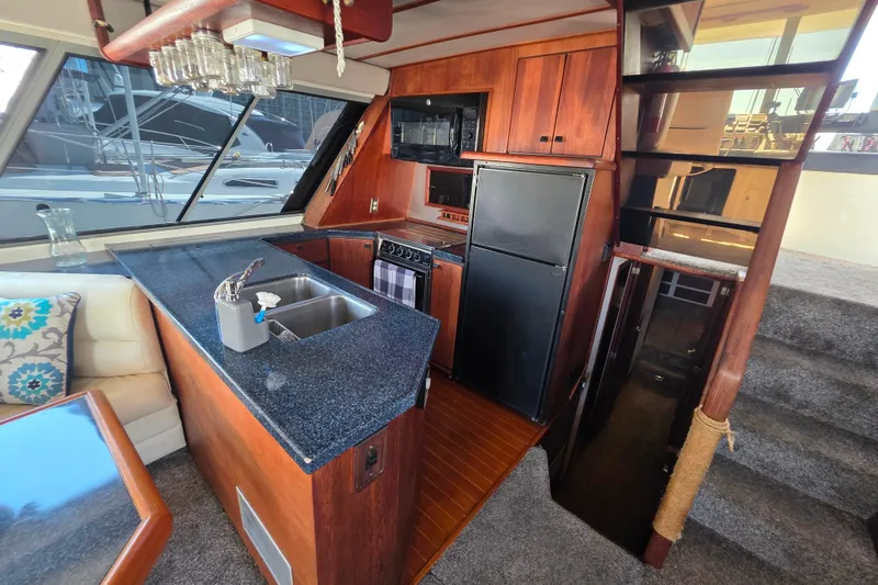 Slide: The Image of 1985 Bayliner 4550 Motoryacht interior with kitchen, stairs, and seating area. - 12
