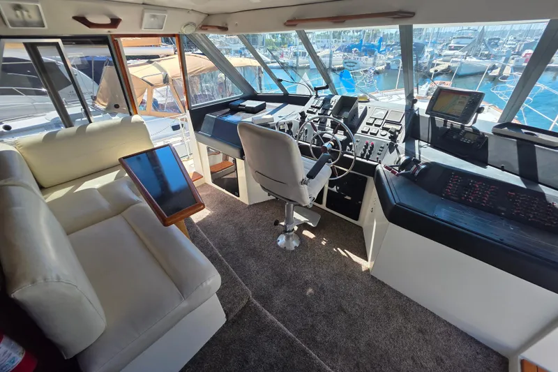 Slide: The Image of Interior of 1985 Bayliner 4550 Motoryacht with helm, seating, and marina view. - 14