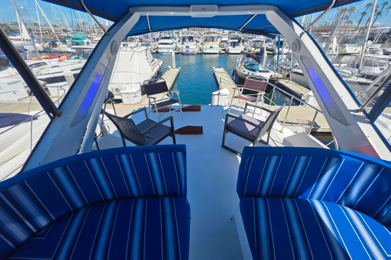 Slide: The Image of 1985 Bayliner 4550 Motoryacht interior with blue seating, overlooking marina with docked boats. - 21