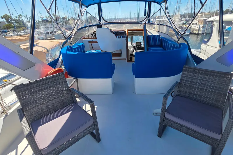 Slide: The Image of 1985 Bayliner 4550 Motoryacht interior with blue seating and wicker chairs in a marina setting. - 23