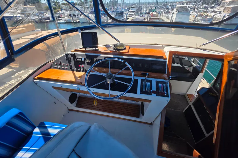 Slide: The Image of 1985 Bayliner 4550 Motoryacht helm with steering wheel, controls, and marina view. - 24
