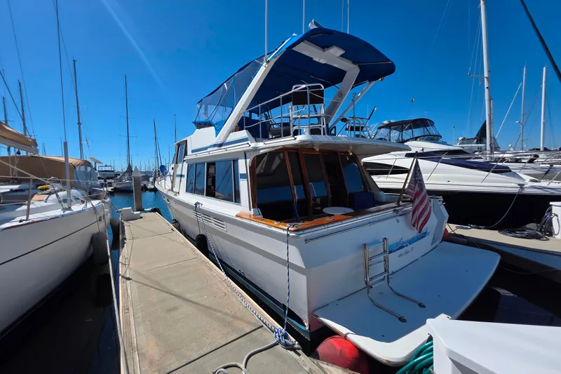 Slide: The Image of 1985 Bayliner 4550 Motoryacht docked at marina under clear blue sky. - 5