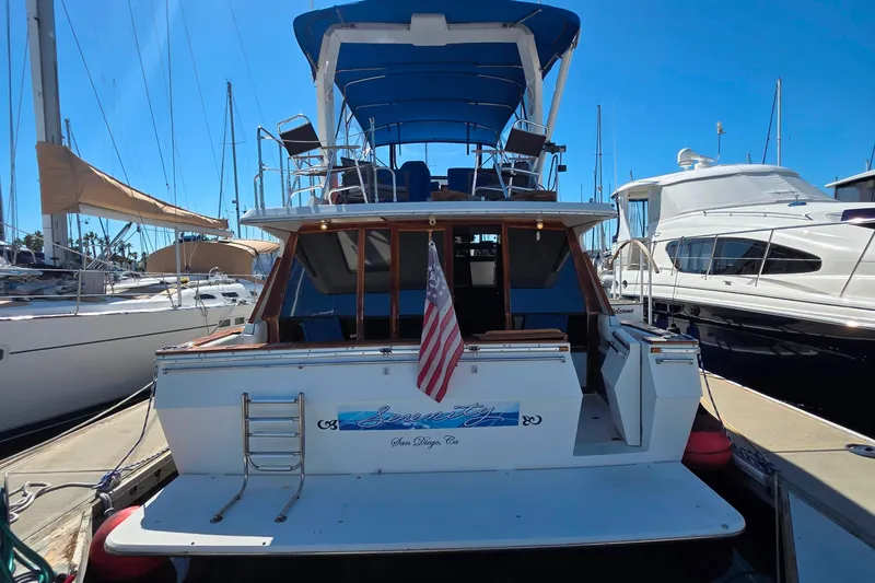 Slide: The Image of 1985 Bayliner 4550 Motoryacht docked, rear view with American flag, blue canopy. - 6