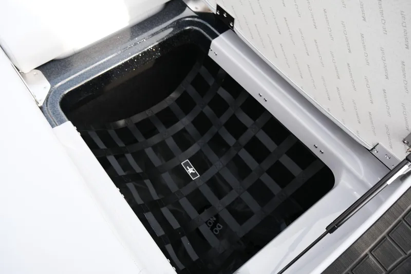 Slide: The Image of Open storage compartment in 2026 MasterCraft XT24 boat, featuring a black netted interior. - 36