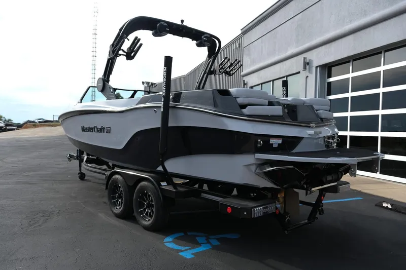 Slide: The Image of 2026 MasterCraft XT24 boat on trailer, parked outside a modern building. - 51